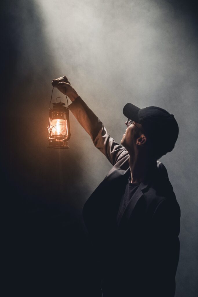 A man with a black hat holding a lantern